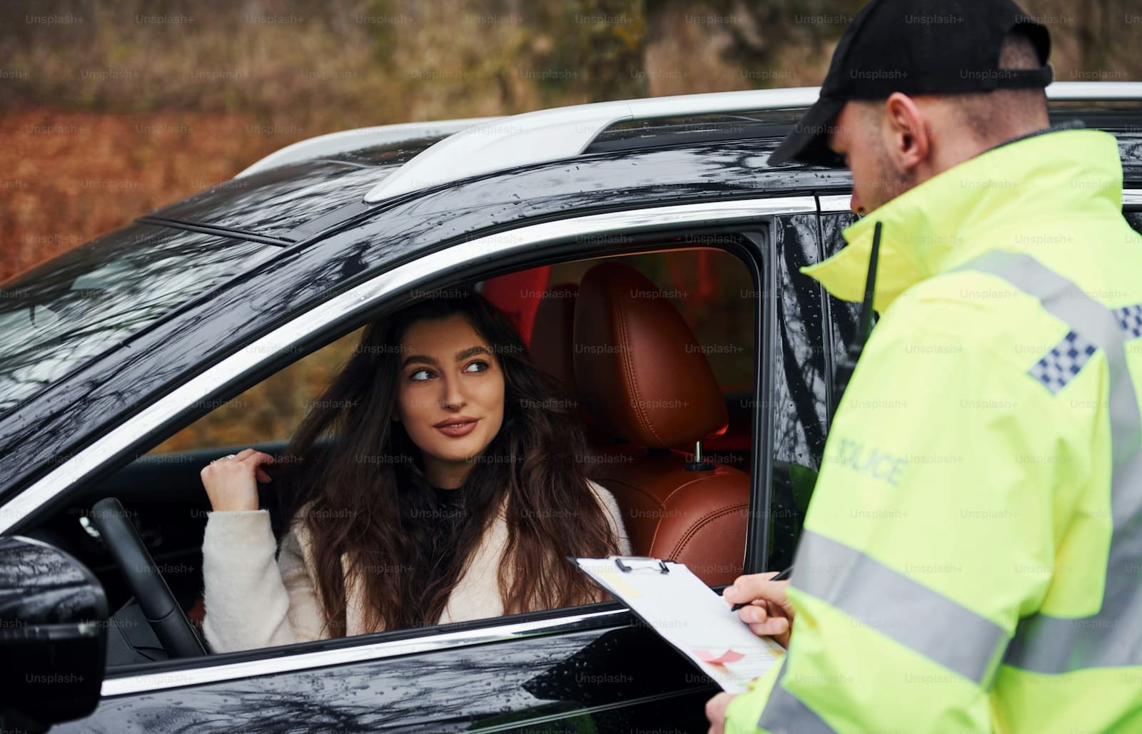Traffic officer in yellow safety vest speaking with female driver during roadside stop